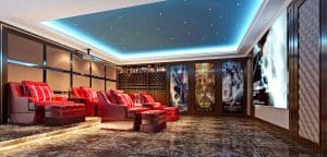 Luxury home theater with red leather recliners, marble flooring, a backlit blue tray ceiling with lights, a large projection screen, and framed movie posters along the walls.