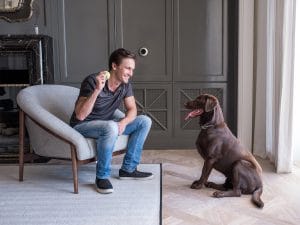 Man with his dog in a living room featuring voice-controlled smart home technology.