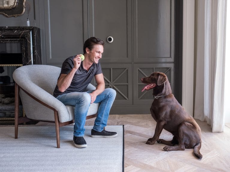 Man with his dog in a living room featuring voice-controlled smart home technology.